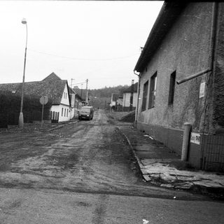 Rural street with empty road, old buildings, and sparse surroundings.