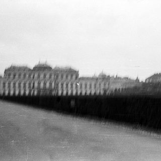 Blurred urban scene with blurred figures near historic buildings.