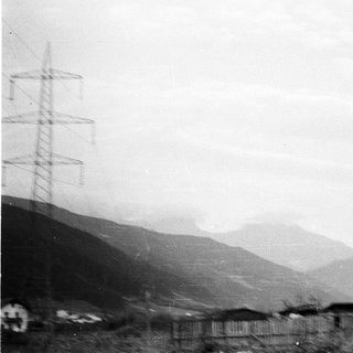 Rural landscape with mountains, power lines, and scattered buildings.