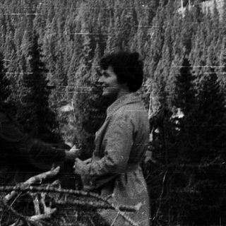 Two people riding bicycles through a forested mountain landscape.