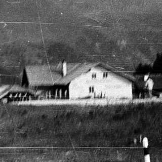 Rural roadside scene with house and mountainous backdrop.