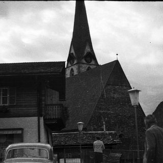 Alpine village scene with church steeple and wooden buildings.