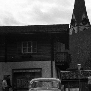 Alpine village scene with church steeple and wooden buildings.