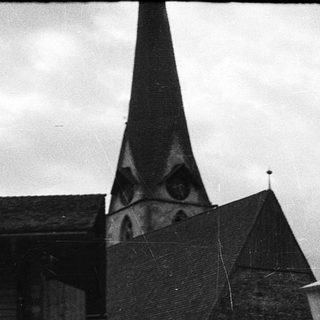 Alpine village scene with church steeple and wooden buildings.