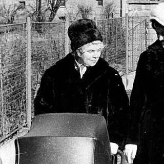 Two women pushing a cart in urban residential area.
