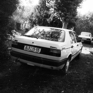 Damaged car parked in debris-filled driveway.