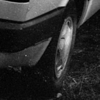Damaged car parked in debris-filled driveway.
