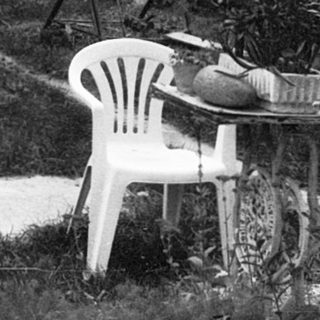 Secluded outdoor table and chairs in wooded area.