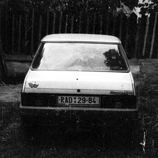A parked car in a muddy, overgrown driveway.