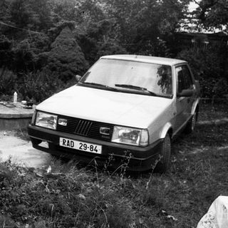A parked car in overgrown, neglected outdoor area.