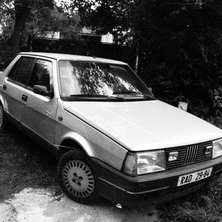 Vintage hatchback car parked in wooded area.