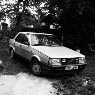 Vintage car parked near rustic campsite.