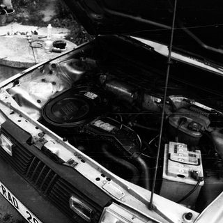 Old car engine exposed in garage setting.