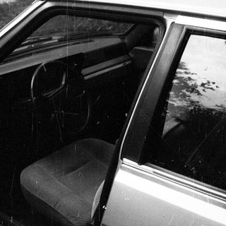 Open car door in rain with empty front seat.