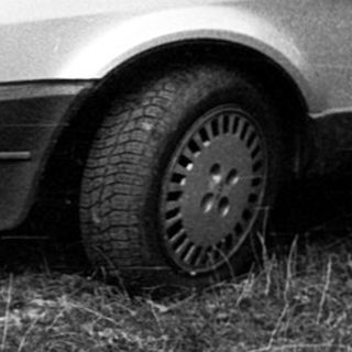 Old sedan parked on overgrown grass.