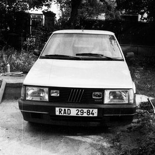 Vintage car parked on gravel driveway.