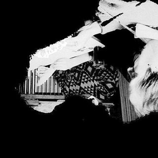 "Blurred grayscale image of a seated person writing."