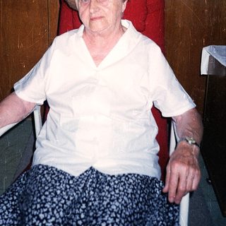 Elderly woman seated in wheelchair indoors.