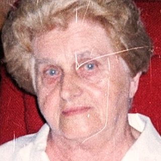 Elderly woman seated in wheelchair indoors.