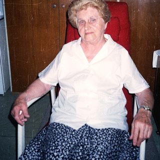 Elderly woman seated in wheelchair indoors.