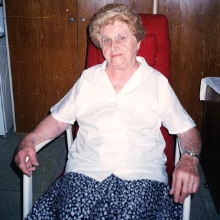 Elderly woman seated in wheelchair indoors.
