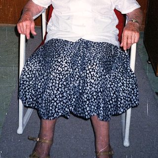 Elderly woman sitting in a wheelchair indoors.