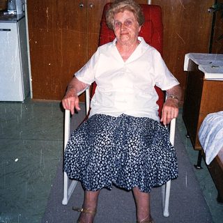 Elderly woman sitting in a wheelchair indoors.