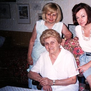 Three generations of women posing indoors together.
