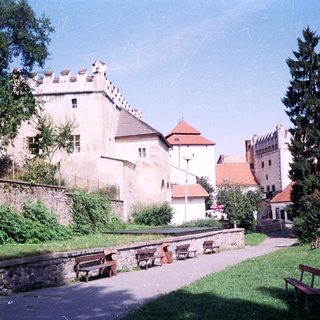 Medieval castle complex with stone towers and courtyard benches.
