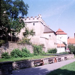 Medieval castle complex with stone towers and courtyard benches.