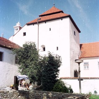 Medieval-style stone tower with white walls and red roof.