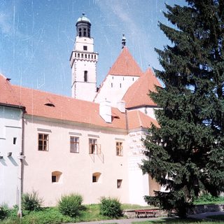 Historic castle with red-tiled roofs and tower.