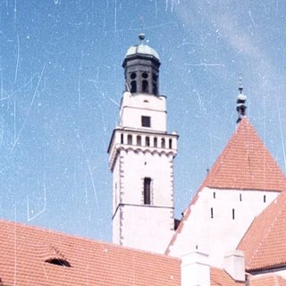 Historic castle with red-tiled roofs and tower.