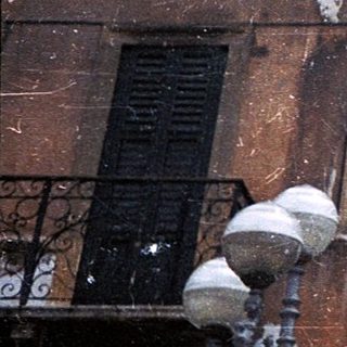 Historic building facade with faded frescoes and gelateria shop.