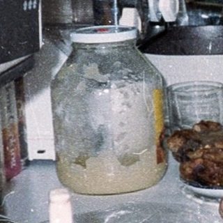 Man cooking in a busy, cluttered kitchen.