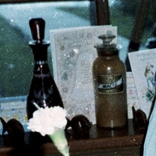 Woman sitting by birthday cake and floral centerpiece.