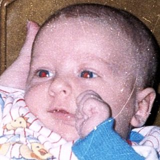 A woman holds a baby indoors.