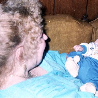 A woman holds a baby indoors.