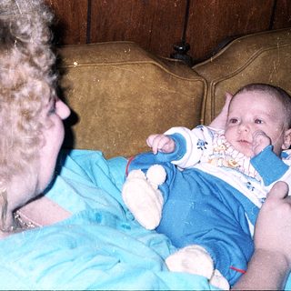 A woman holds a baby indoors.