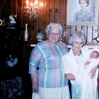 Four women posing with a baby indoors.