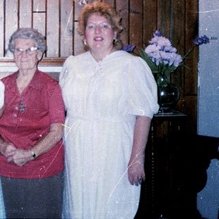 Four women posing with a baby indoors.