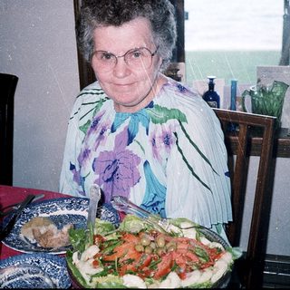 Woman posing with birthday cake and salad.
