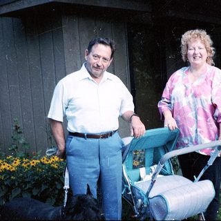 Couple pushing baby stroller outside home.