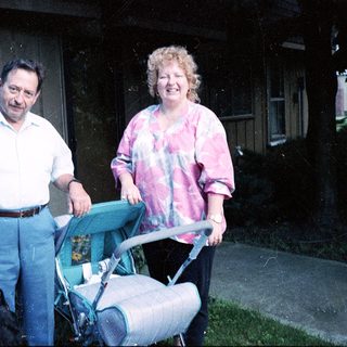 Couple pushing baby stroller outside home.