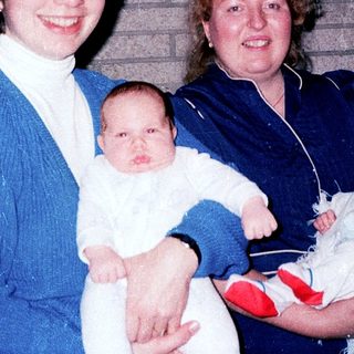 Two women holding newborn babies indoors.