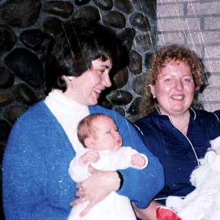 Two women holding and smiling with twin babies.