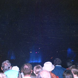 Crowd watching stage with colorful lighting.