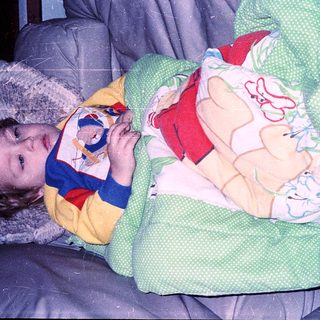 Child snuggled under winter blanket with stuffed toy.