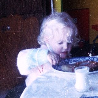 Two children eating cake at a table indoors.
