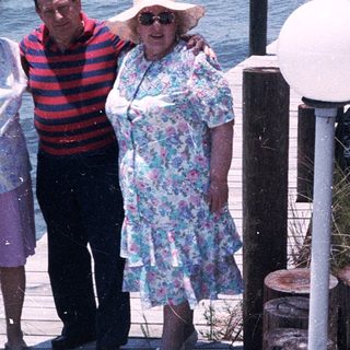 Three people posing on a seaside boardwalk.